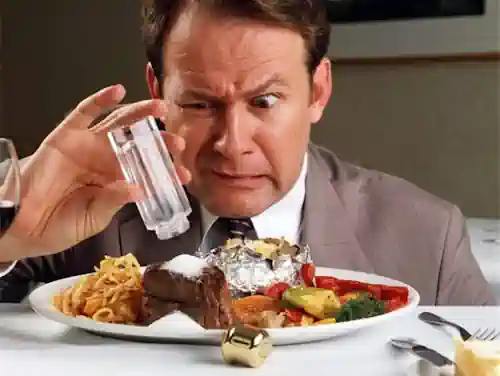 persona poniendo mucha sal a la comida